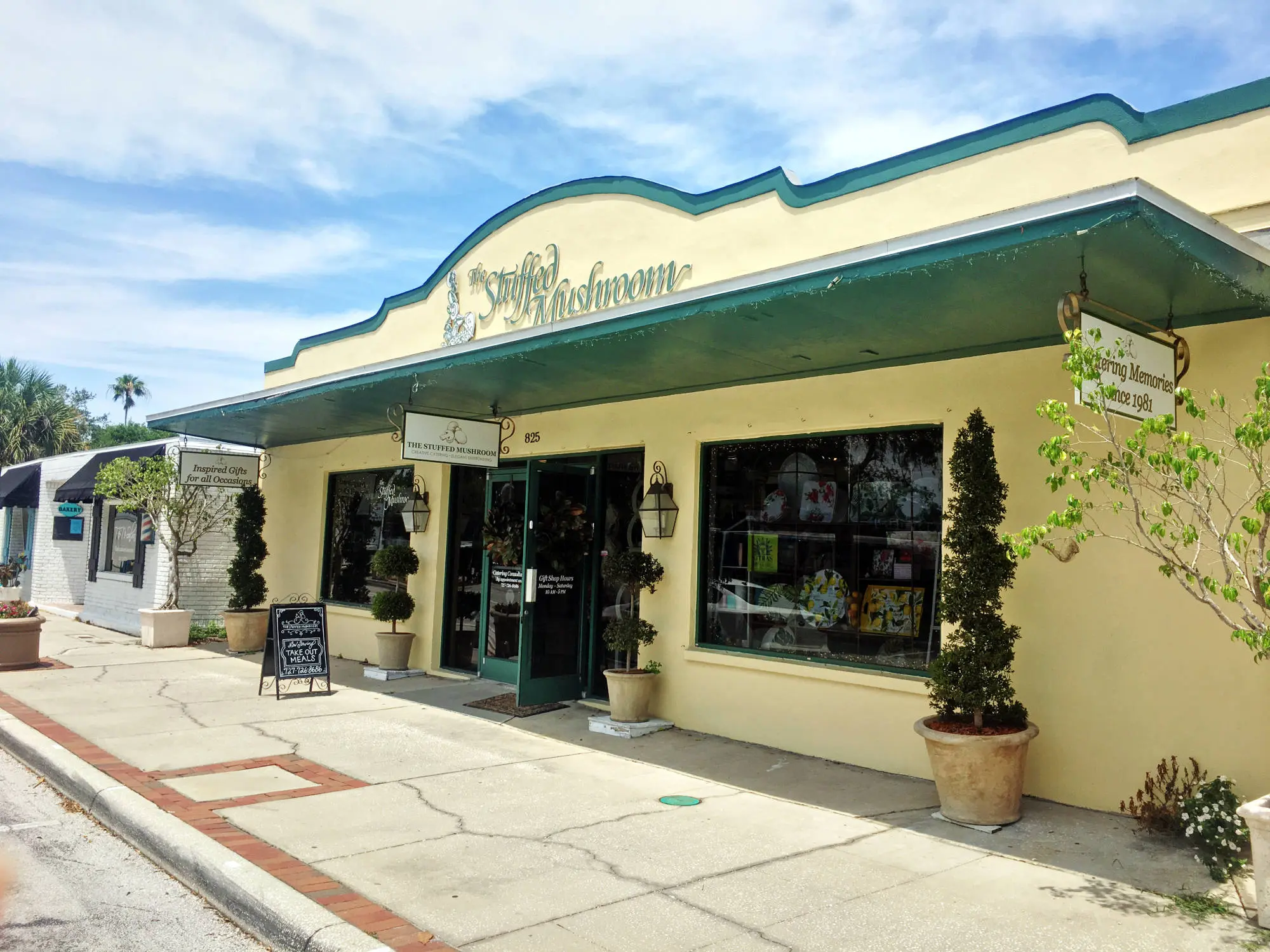 Yellow storefront with teal accents and plants.